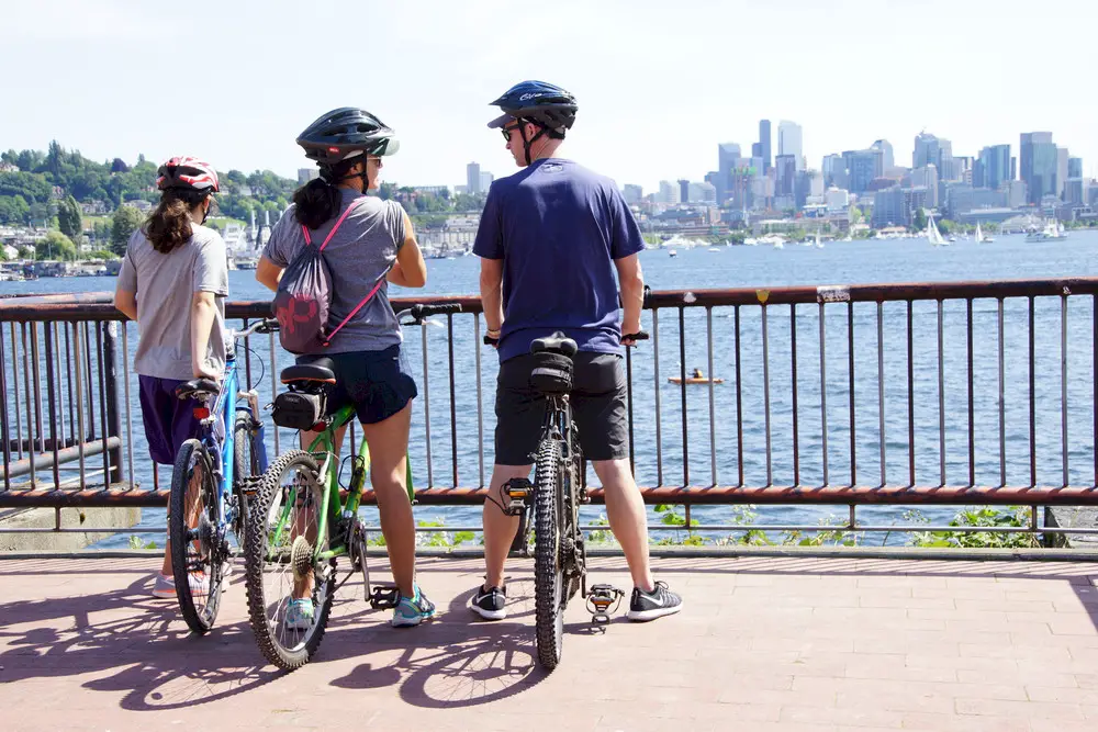 A family of three biking to the Seattle waterfront at Gasworks Park, overlooking the Seattle skyline