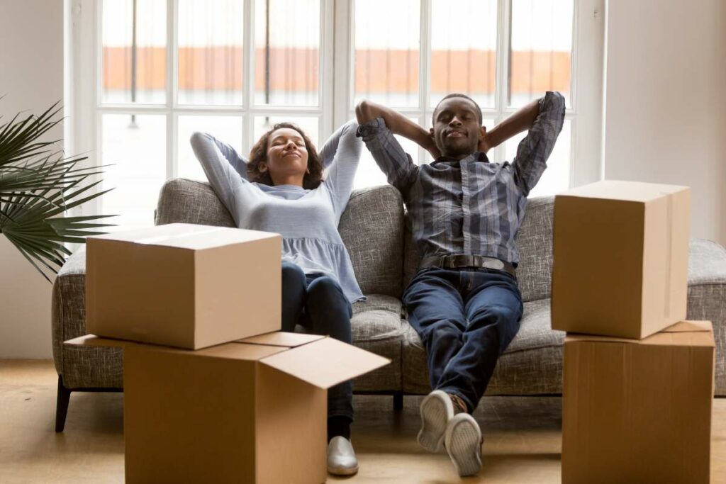 A couple relaxing on the couch with moving boxes around them